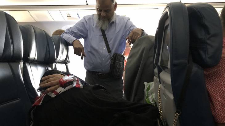 Man stand so wife can sleep on plane