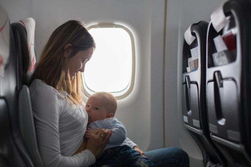 mom breastfeeding baby on plane
