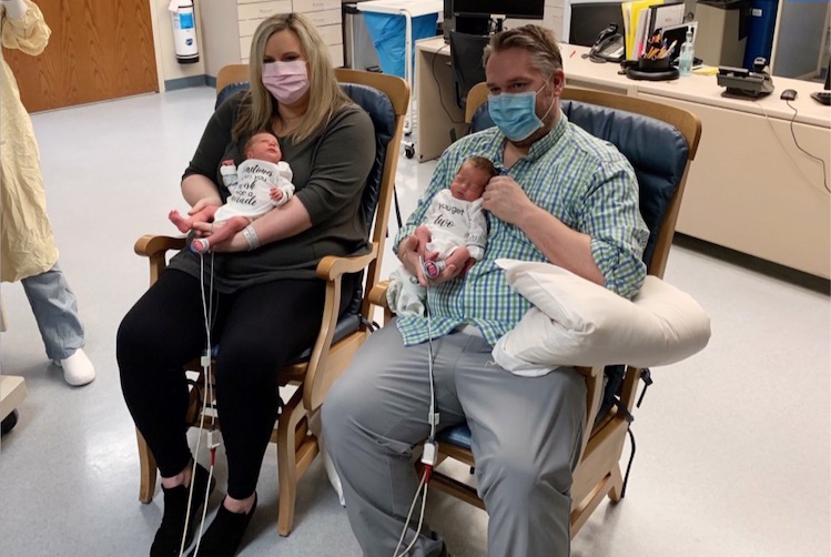 parents who had coronavirus hold twins for the first time, 3 weeks after birth