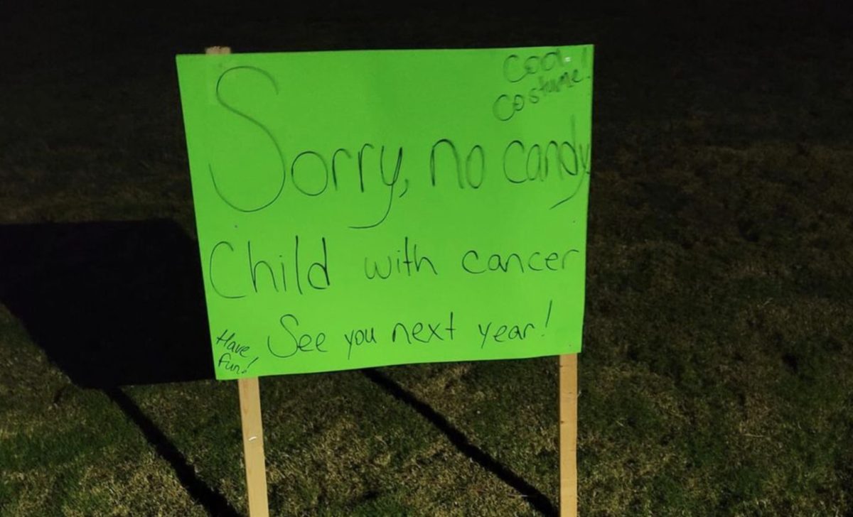 kids dump some of their halloween candy in front of child with cancer sign so that he can enjoy the goodness too