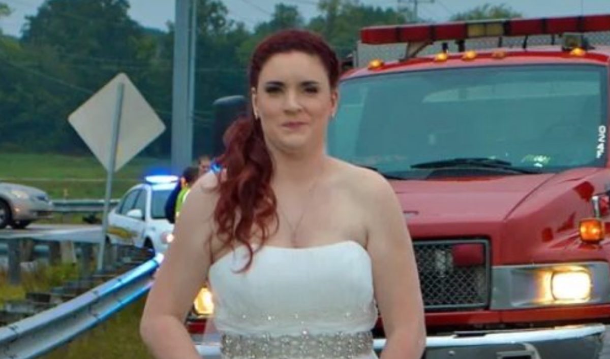 Bride Stuns in Wedding Dress While Aiding Crash Victims on Her Way to Her Reception | You may have already seen this photo of a bride in her wedding dress and shoes with her hair and makeup done and an ambulance and fire truck behind her.