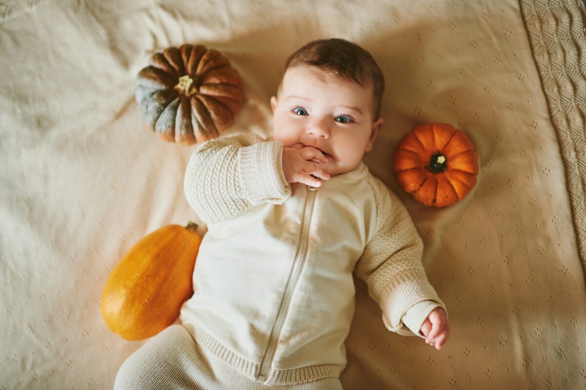 baby laying by pumpkins