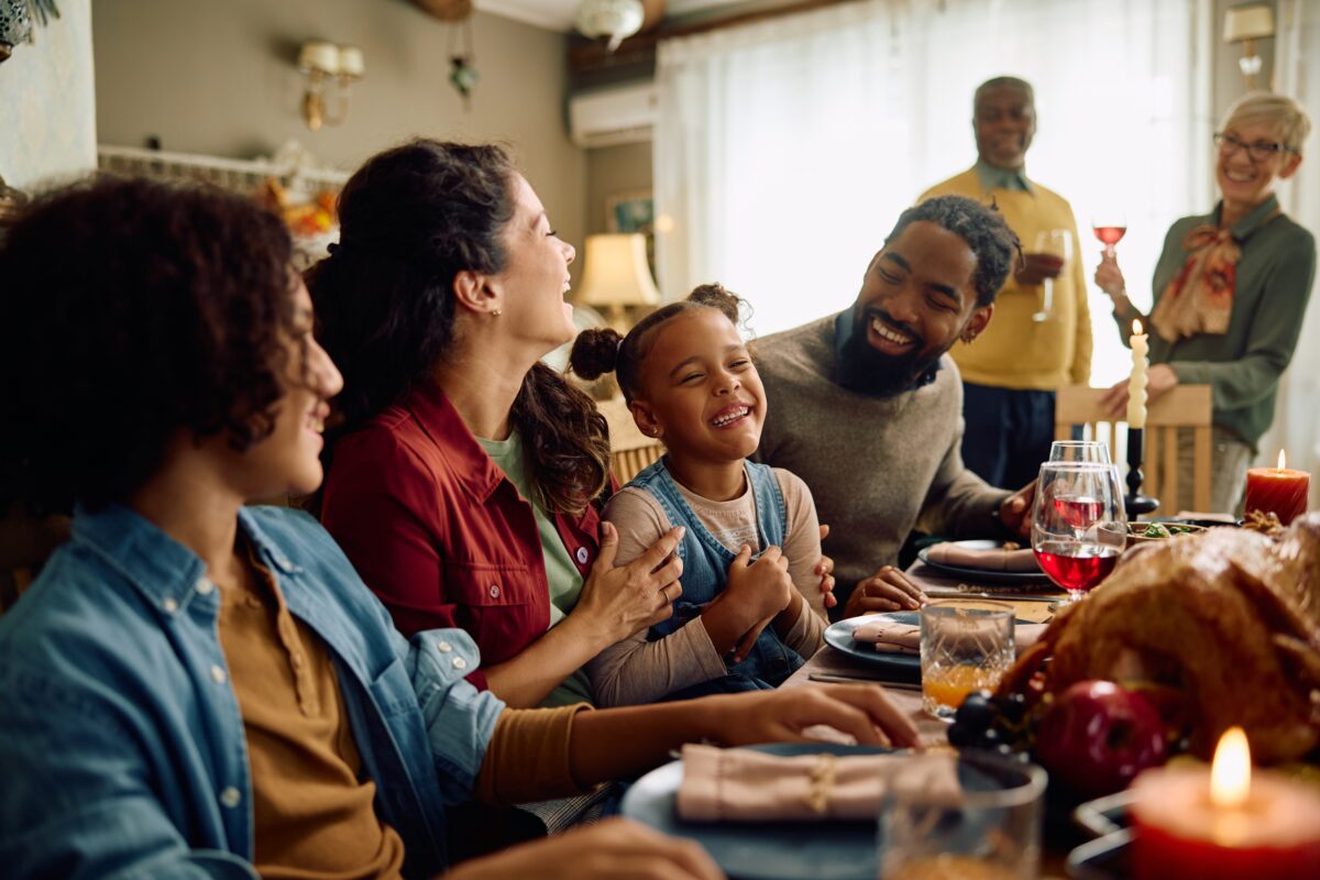 family sitting around dinner table at thanksgiving