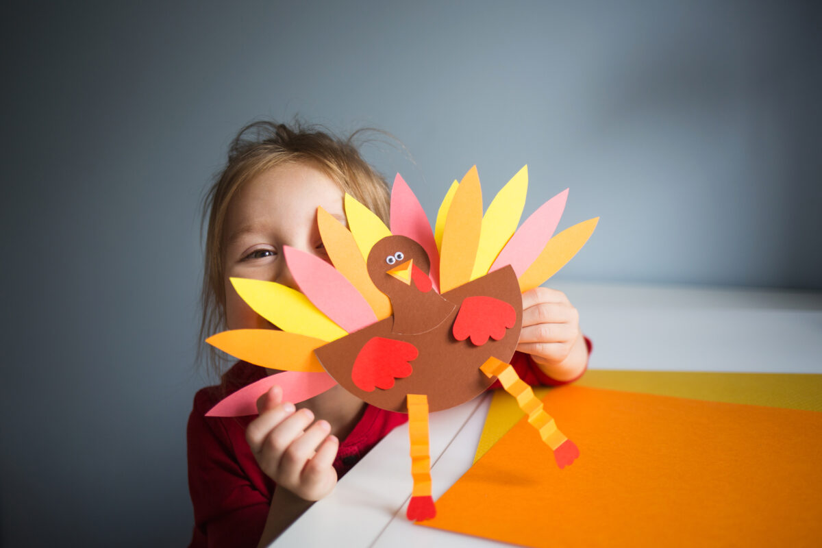 young girl shows off paper turkey